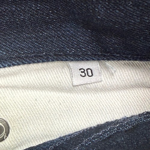 White fabric tag on inner waistband of Gustin jeans, marked “30x29 indigo raw selvedge” with black text.