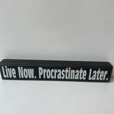 Rustic distressed wooden block sign that reads "Live Now. Procrastinate Later.”