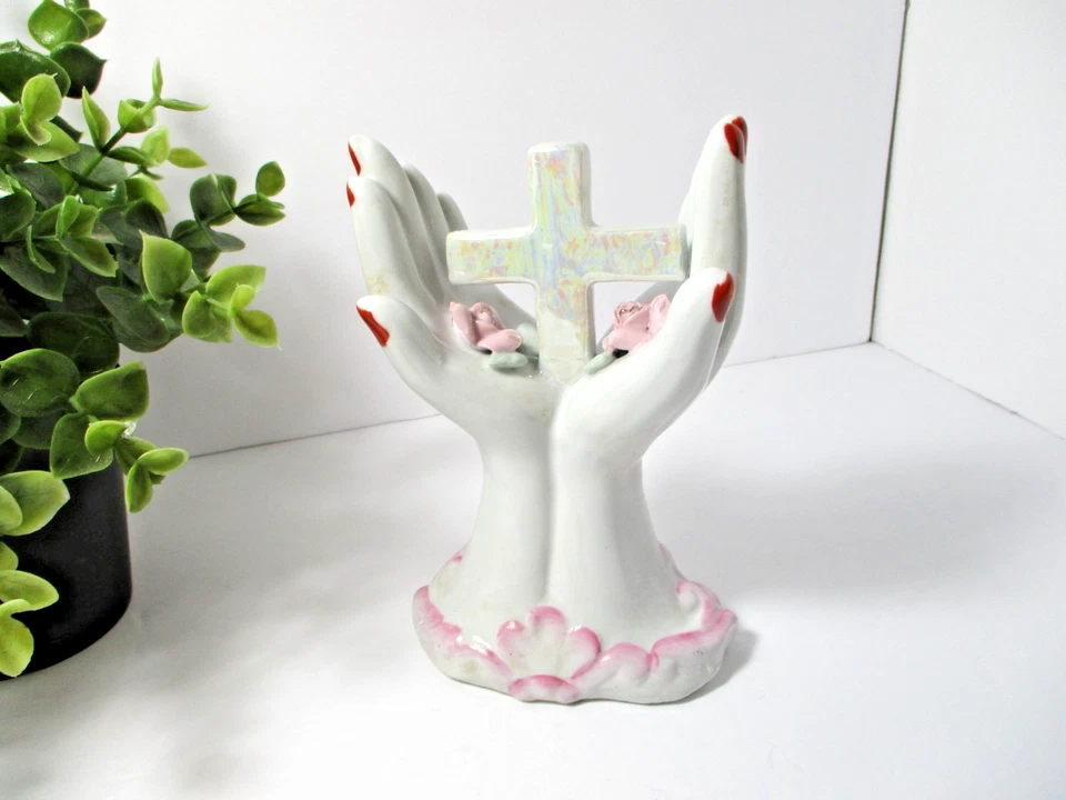 Dos manos de cerámica con clavos rojos sosteniendo una cruz y flores. Foto 3 de 4