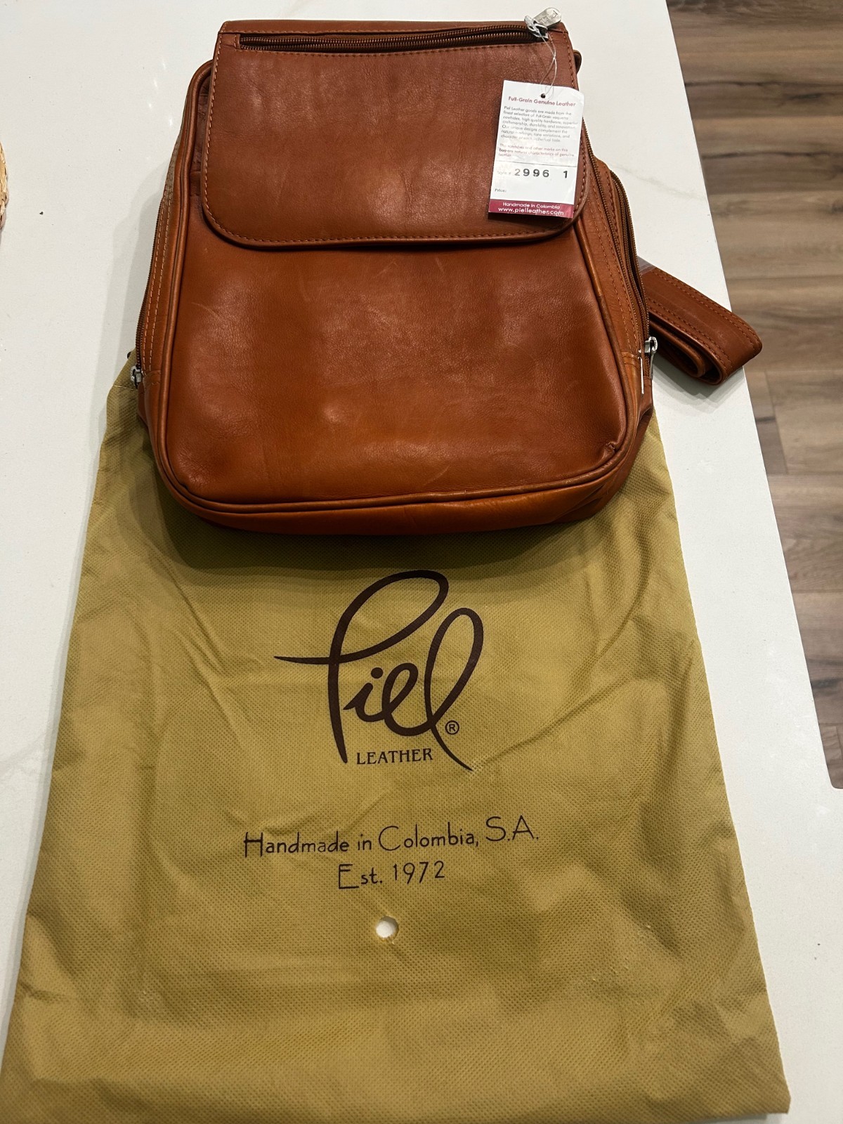 Cognac leather Piel flap-over tablet backpack, shown with its cloth dust bag.