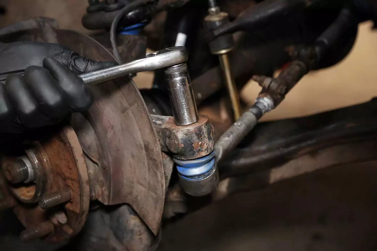 A mechanic removes the tapered pin nut with a socket wrench.