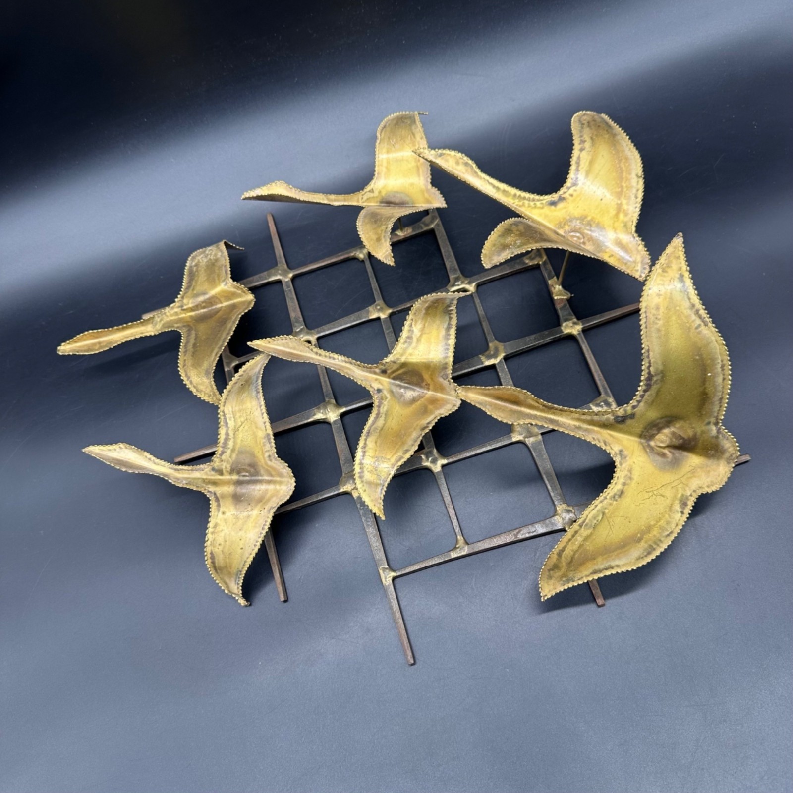 Metal wall sculpture of three abstract birds in flight, cut and welded in a brutalist style.