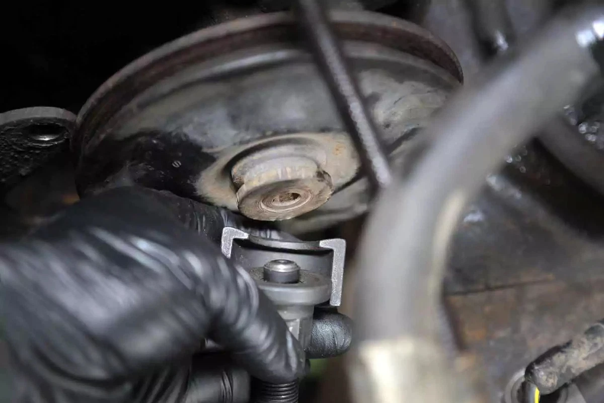 A mechanic uses a puller tool to remove the power steering pump pulley.