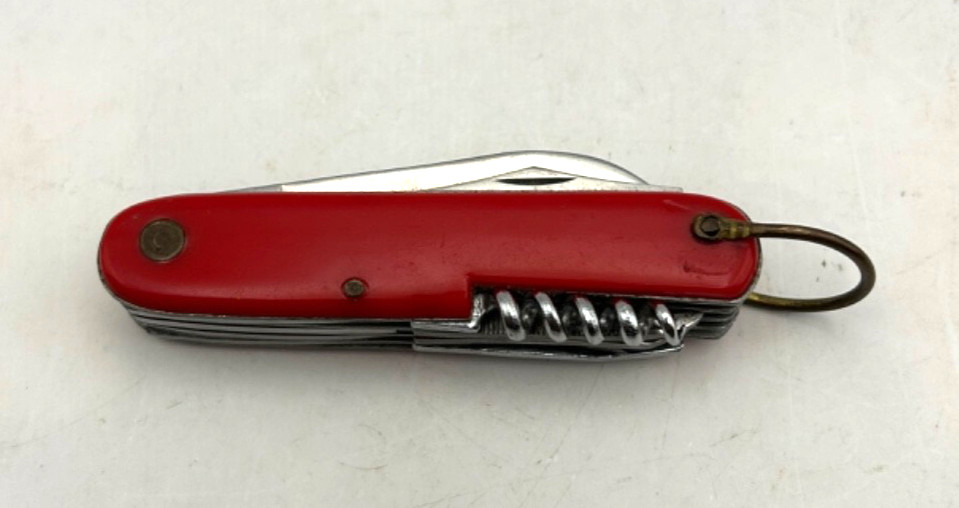 A sleek vintage Japanese stainless multi-tool with a red handle and corkscrew — the kind of well-made pocket knife they just don't manufacture anymore.