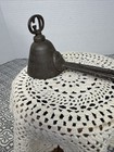 Antique metal ice cream scoop with ornate handle, resting on a white lace-patterned pedestal, made in USA around 1900.