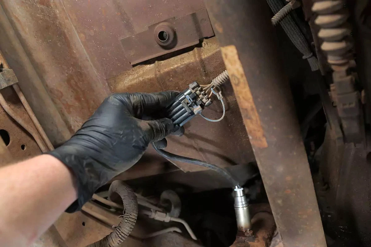 A mechanic plugging the new sensor into the vehicle’s wiring harness.