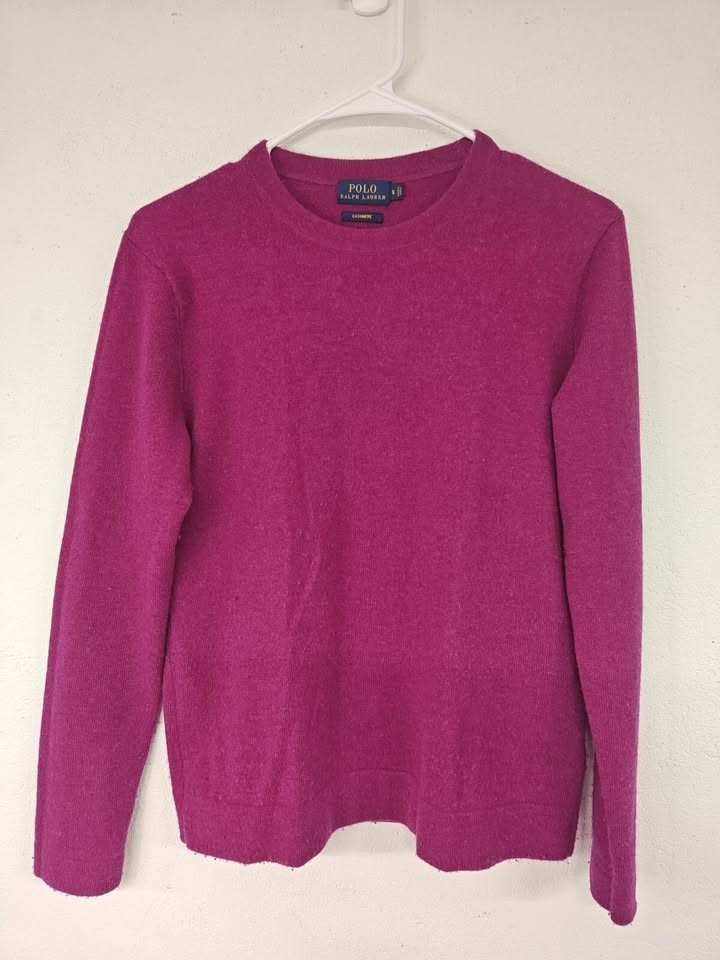 Magenta cashmere crewneck sweater on a hanger.