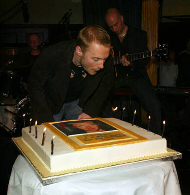 Ronan Keating blows candles out on a cake as he at the launch par- 2004 Photo