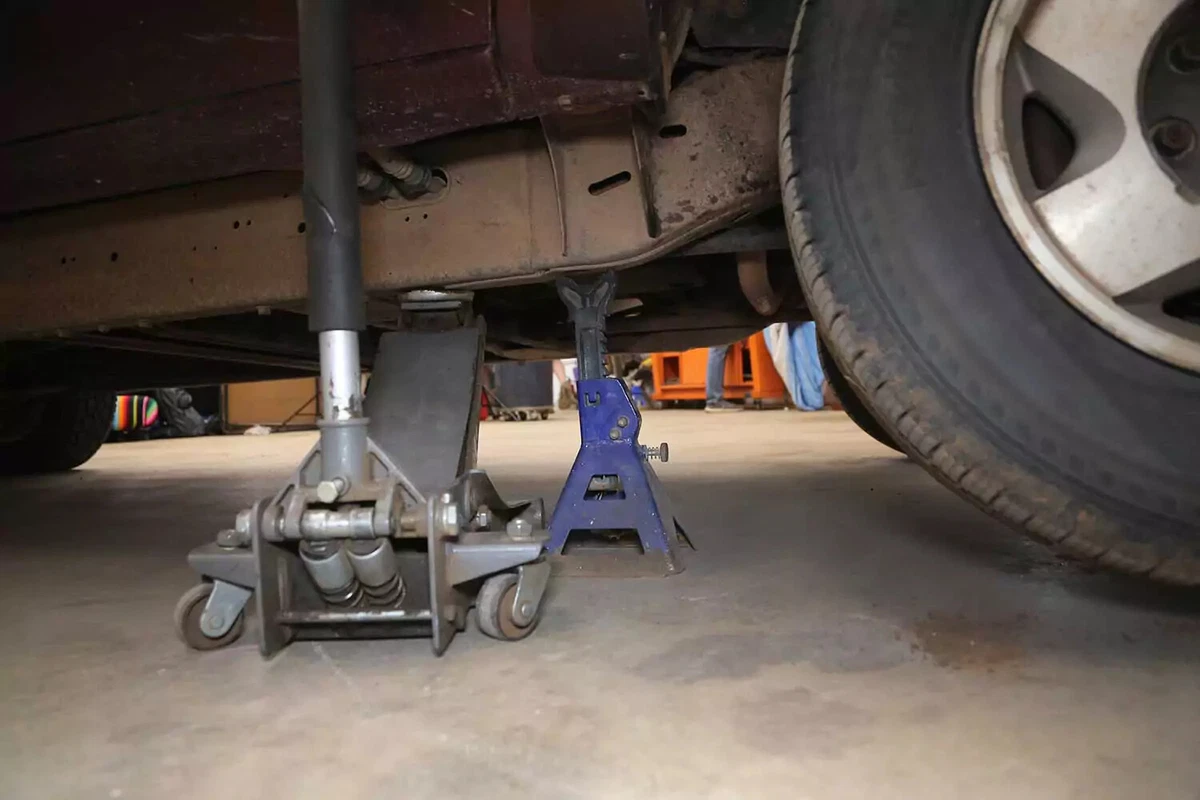 A vehicle raised with a floor jack and a jack stand.