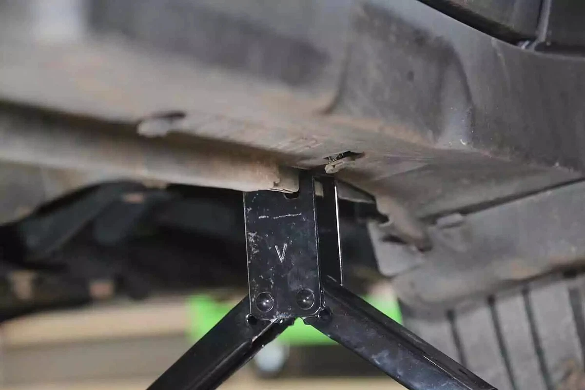 A jack at the jack points underneath a vehicle.