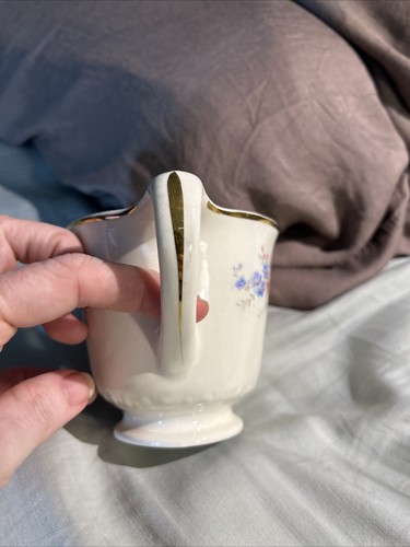 Cream ceramic mug with gold rim, floral print in blue and white, and “Made in U.S.A.” text on handle.