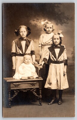 Postcard RPPC Four Sisters Siblings Real Photo Baby in Chair Hair Bows