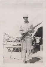 WW2 Photo of Helmeted Soldier Cradling Rifle At Desert Tent Camp