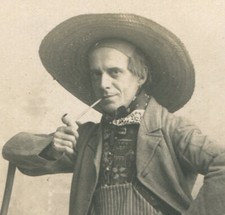 MAN IN HAT GETTING READY TO SMOKE WHILE LEANING ON BROOM. POST CARD.