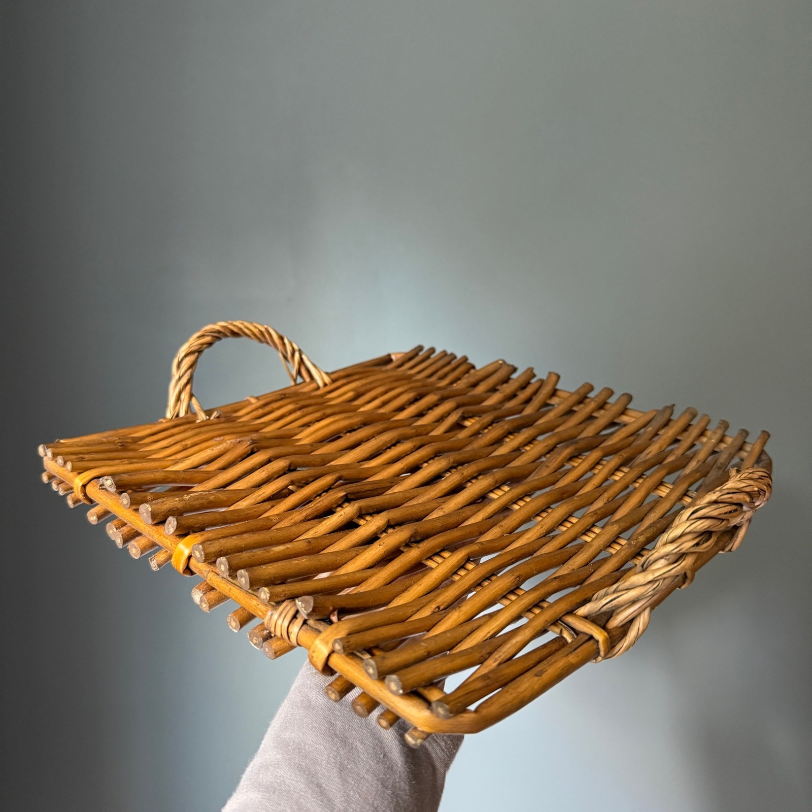 Brown woven rattan wicker serving tray with handles.