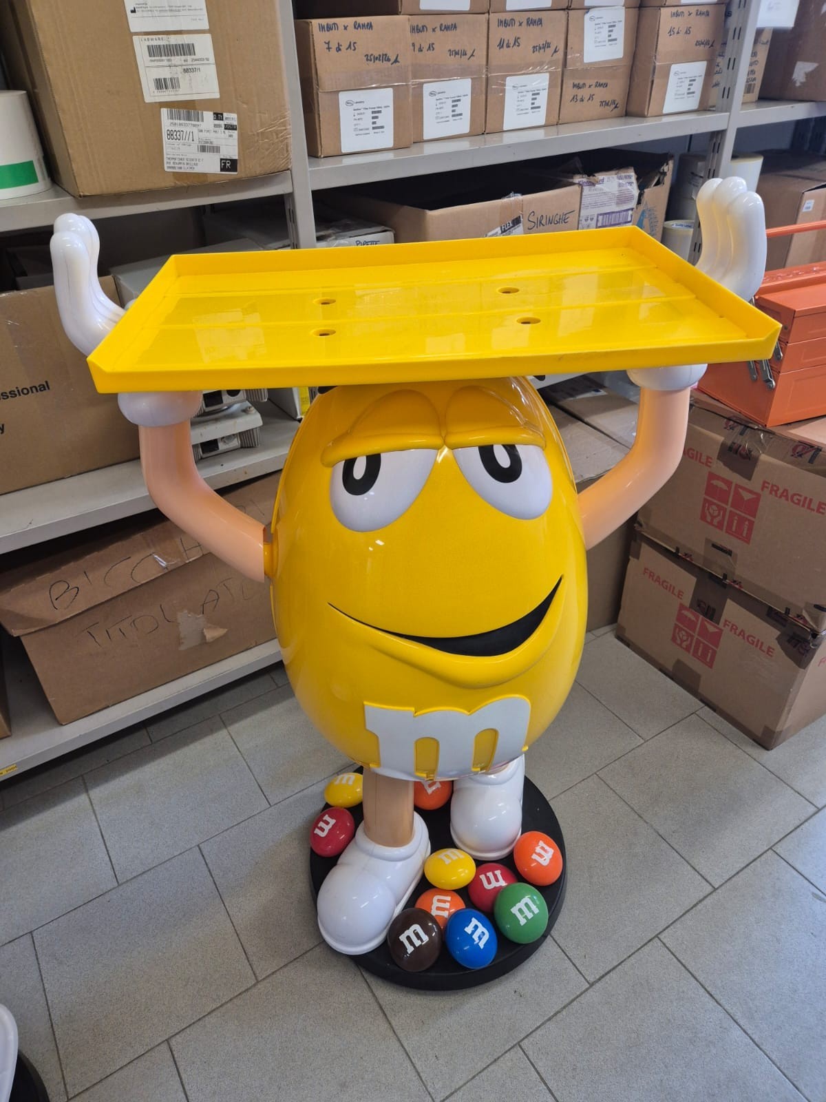 Statua personaggio M&M’s giallo con vassoio giallo su base con confetti