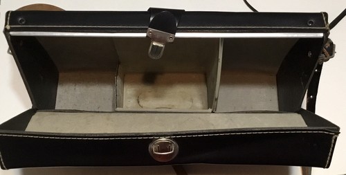 Black vintage hard camera case with two front pockets, stitched edges, and “Made in U.S.A.” text on top.