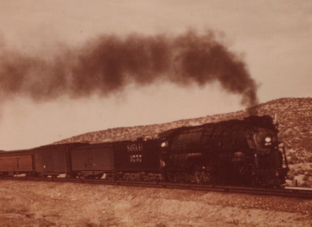 Vintage Steam Locomotive Chugging on Track with Smoke and Mountain Backdrop in Sepia Tone-image