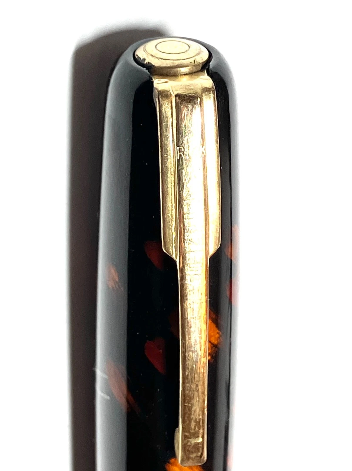 Black vintage fountain pen with gold accents, closed ink shut off, and subtle orange swirled pattern on body.