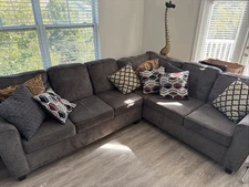 large, L-shaped sectional sofa upholstered in dark gray fabric.