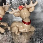Pair of brown reindeer figurines with large antlers, red ribbons, and small red flowers on their heads.