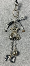 silver-colored metal teddy bear keyring with a bow and charms.