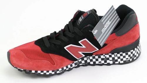 Red and black New Balance 1300 sneaker with white laces, silver tags, and black-and-white checkered sole, size 9.