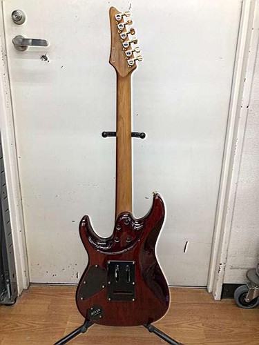 Ibanez AZ47P2K Dragoneyeburst used electric guitar with mahogany back, six strings, and gold hardware on stand.