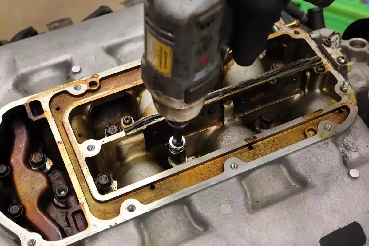 A mechanic tightens the intake manifold bolts with an impact driver.