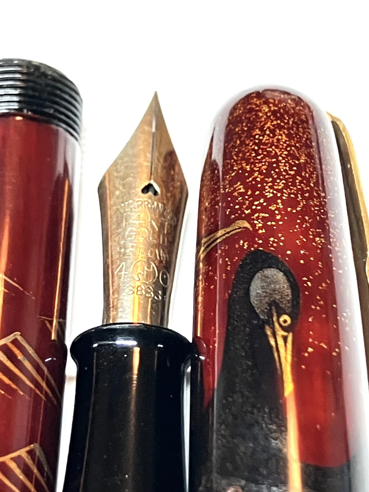 Vintage ink shut off fountain pen with gold nib, black body, and ornate brown handle on a white background.