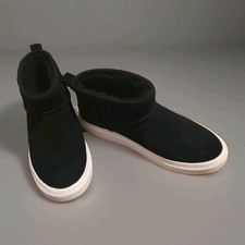 Mini Botas UGG Alameda para Mujer en gamuza negra con suela deportiva blanca gruesa.