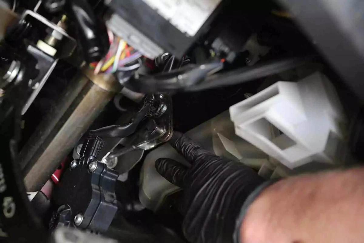 A mechanic wearing a black gove reattaches the clevis pin to the clutch master fork.