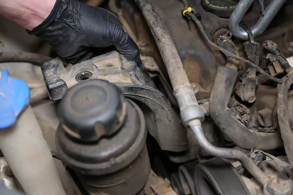 Mechanic lifting the intermediate bracket away from the motor mount and engine.