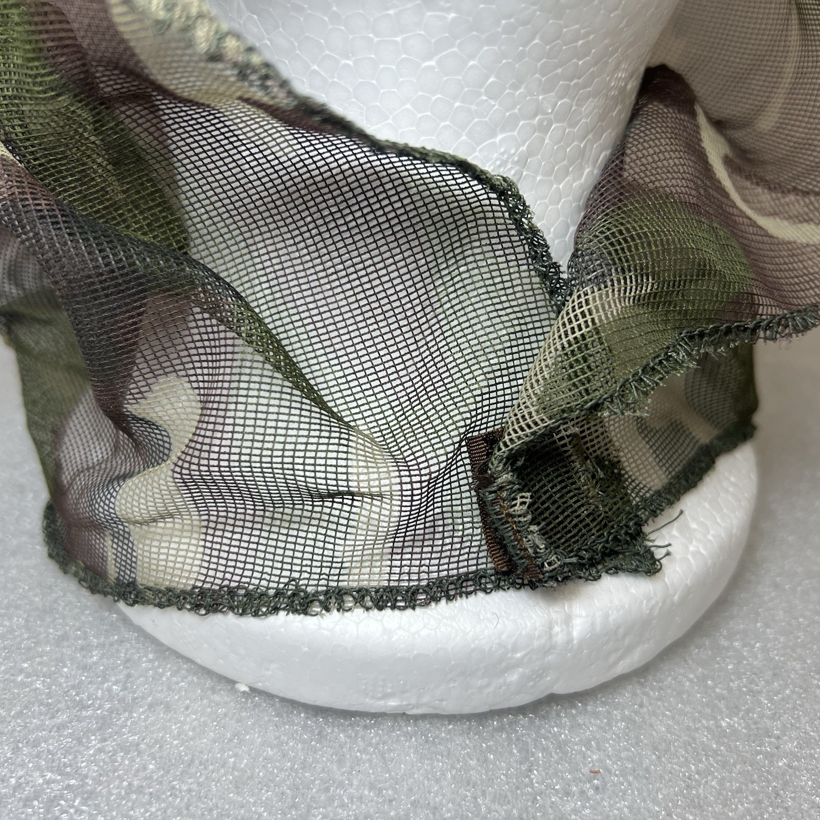 Close-up of Vtg Camo hunting mosquito net with green and brown camouflage pattern and textured mesh fabric.