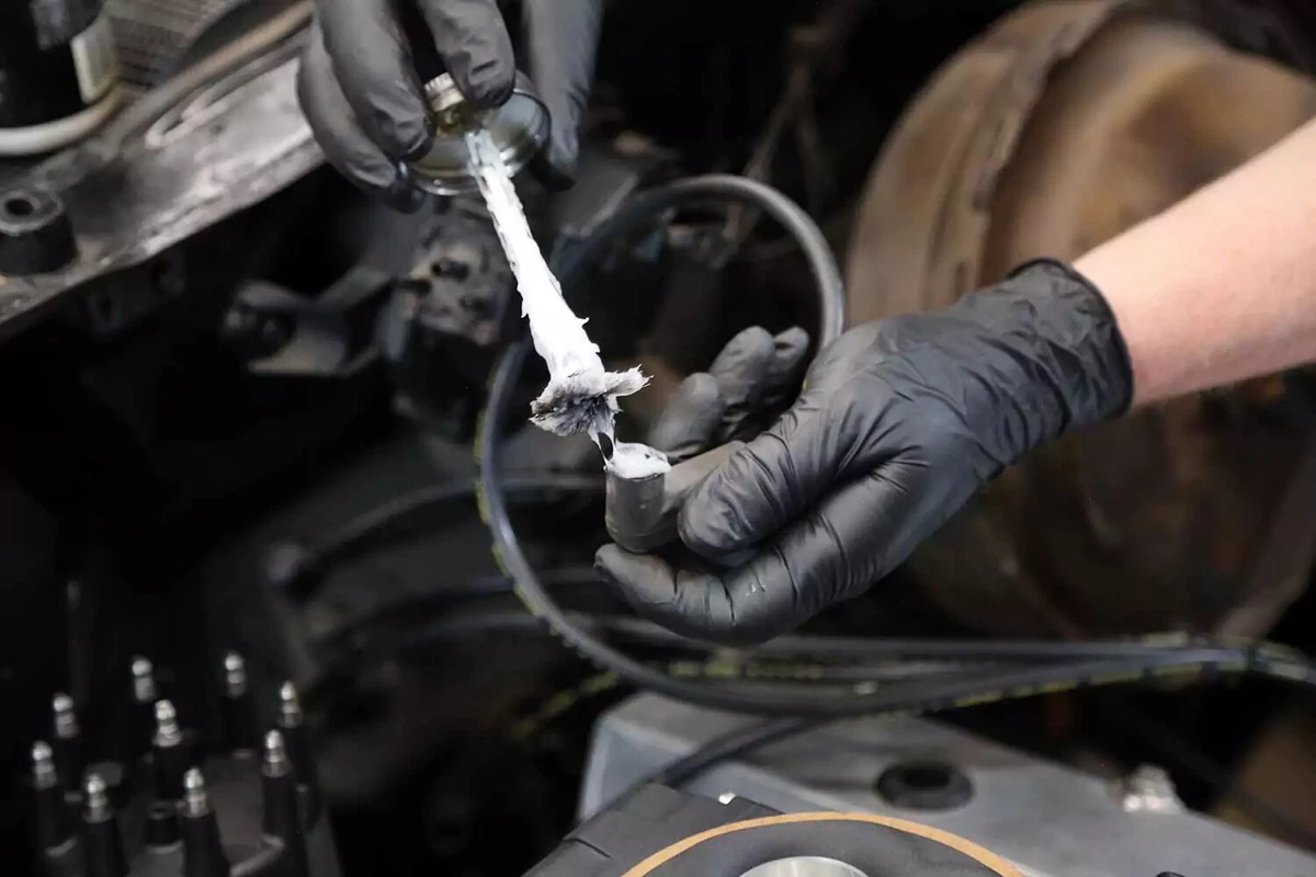 A mechanic applies dielectric grease to a spark plug wire.