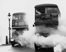 Double-decker buses drive through a smoke screen during a civil de- Old Photo