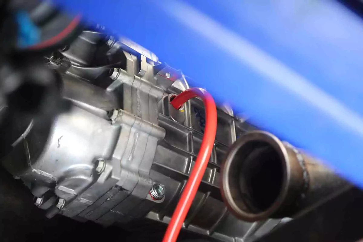 The red spout of a transfer pump inserted into the filter neck of a vehicle's transmission.