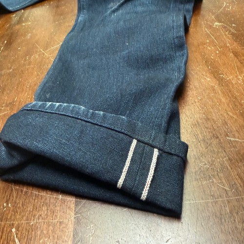 Black denim Gustin men’s 30x29 slim-fit with white contrast stitching and button closure on wooden surface.