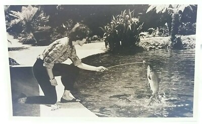 Vintage Foto glamouröse Dame füttert einen Fisch, der aus einem Teich springt, um 1950 