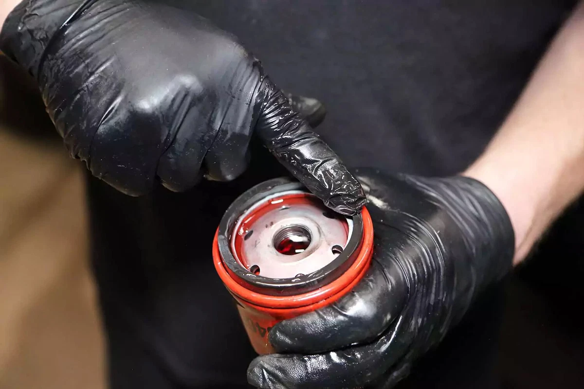 A mechanic wipes fresh automatic transmission fluid on the filter’s gasket.