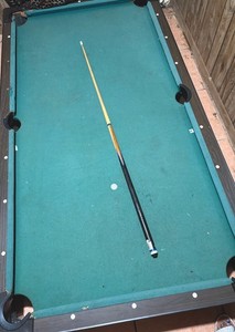 Billiard Table with Green Felt, Black Frame, and Cue Stick for Pool Game Room