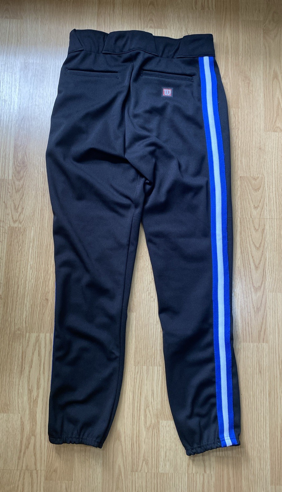 Black Wilson RMB A4409 men’s baseball pants with blue and white vertical stripes on the back, made in USA.
