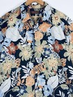 Dark blue Hawaiian shirt with orange, yellow, and white floral print, green leaf pattern, and brown collar on wooden hanger.