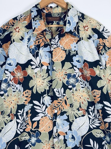 Dark blue Hawaiian shirt with orange, yellow, and white floral print, green leaf pattern, and brown collar on wooden hanger.