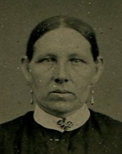 WOMAN WITH EARRINGS AND AUSTERE APPEARANCE. TINTYPE IN PERIOD PAPER MAT.