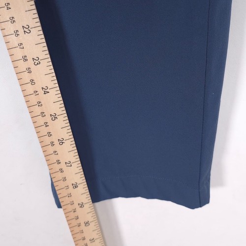 Measuring blue Theory men’s dress pants at 32 slim fit with dark vertical seam, using yellow ruler with black markings.