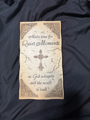 decorative wall plaque featuring religious text and a cross.