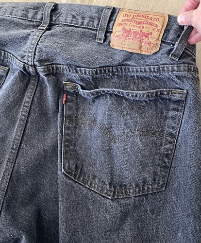Black Levi’s 501 XX with red back pocket, brown leather patch, and visible red “Levi’s” branding.