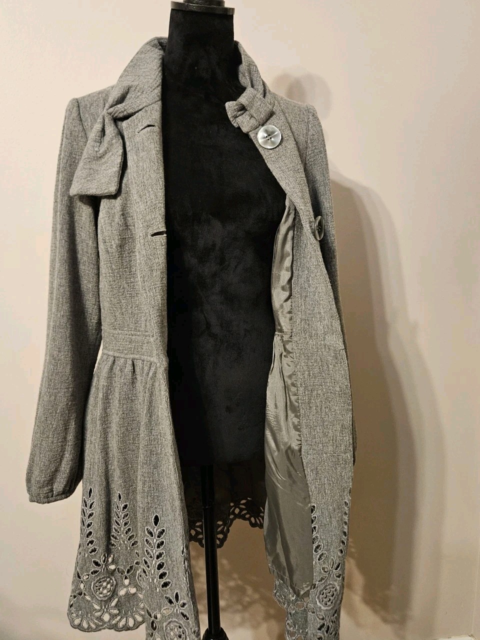 Gray wool blend women’s short coat with high collar, front button closure, and floral edge detailing on sleeves and seams.