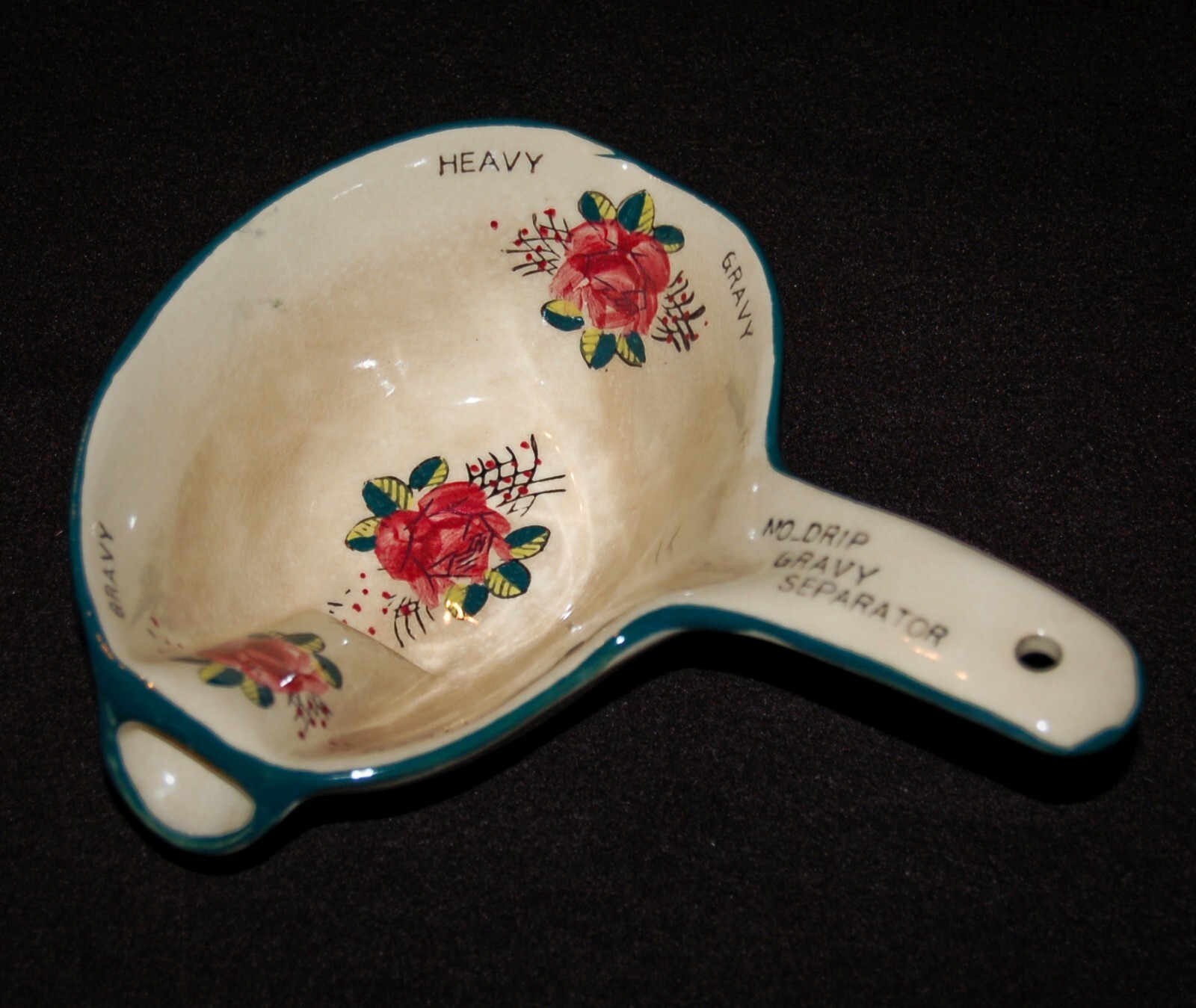 White ceramic gravy separator with red and green floral pattern, teal rim, and text “NO.DRIP GRAVY SEPARATOR” in white.